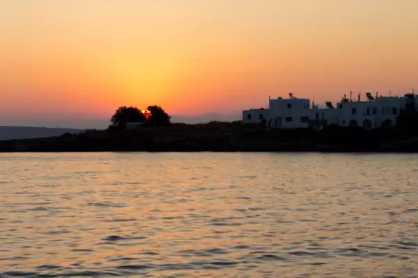 Sonnenuntergang mit rotem Himmel über der griechischen Hafenstadt Naoussa auf Paros & dem Mittelmeer im Vordergrund