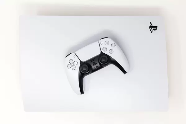 Sony DualSense Wireless-Controller auf einer liegenden Sony PlayStation 5 auf weißem Hintergrund Draufsicht