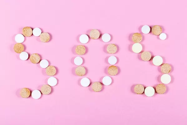 SOS from pills on a pink background
