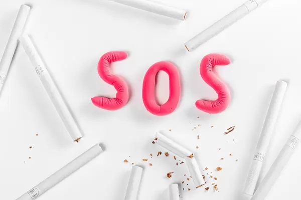Sos of red plasticine on a white background with a frame of cigarettes