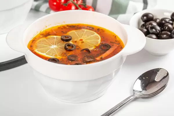 Soup solyanka with meat, sausages, vegetables, pickles, olives and lemon