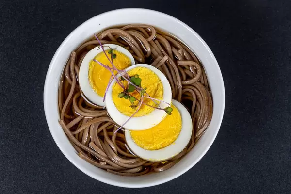 Soup with buckwheat noodles, boiled egg and micro-greens of cabbage, top view