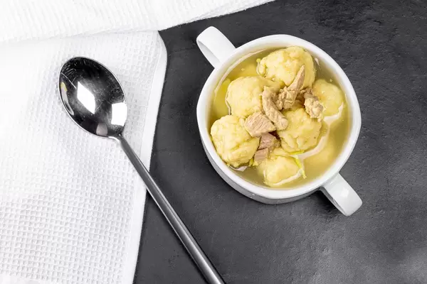 Soup with meat and dumplings on a black background with a white kitchen towel, top view (Flip 2020)