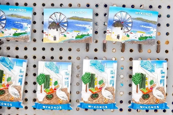 Souvenirs of Mykonos, magnets with windmills and view of the port, alley with goose, plants and fruit