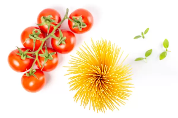 Spaghetti, a branch of tomatoes and basil leaves, top view