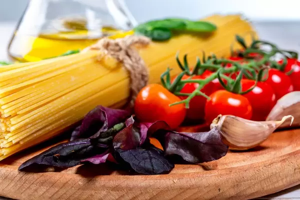 Spaghetti mit Tomaten, Knoblauch, Basilikum und Olivenöl auf einem runden Holzbrettchen