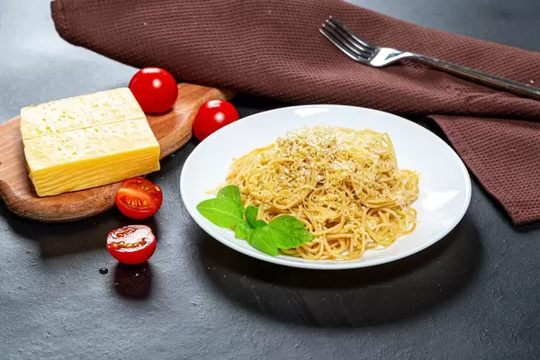 Spaghetti with cheese and sesame seeds on a black background with tomatoes