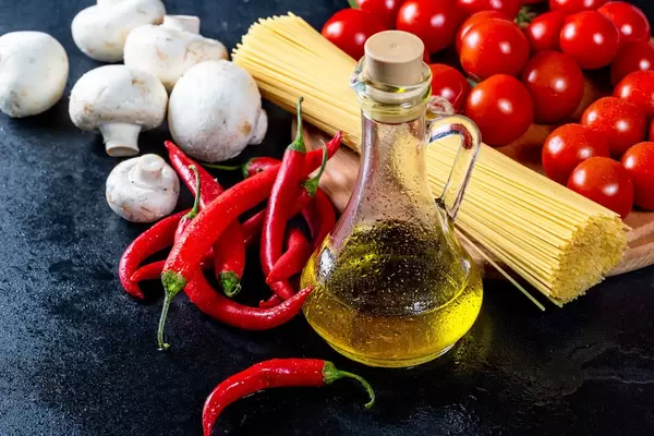 Spaghetti with olive oil and vegetables on black background