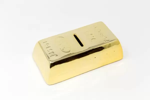 Spardose in Form von Goldbarren vor weißem Hintergrund