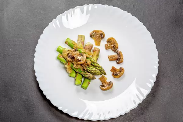 Spargel mit Pilzsauce auf einem weißen Teller auf einem schwarzen Hintergrund Top-view