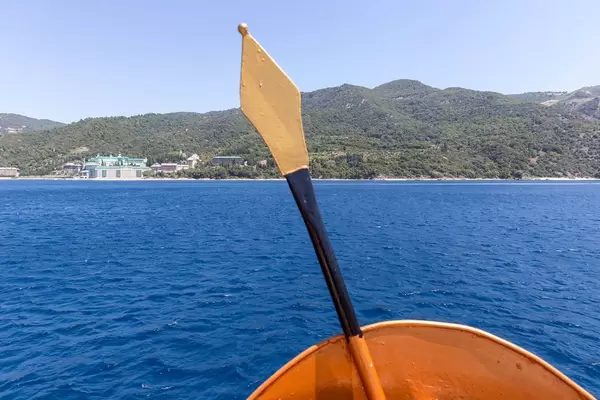 Spartanischer Speer und Schild auf dem Schiff und das Kloster Agios Panteleimon im Hintergrund