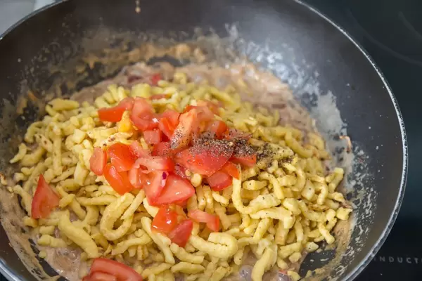 Spätzle mit cremiger Soße und Tomaten werden im Wok zubereitet