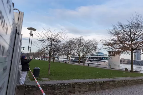 Spaziergängerin fotografiert den Rhein bei hohem Pegelstand