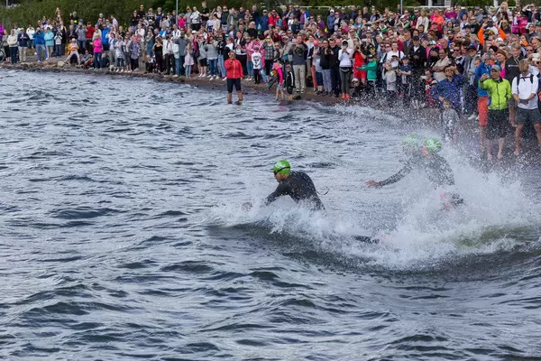 Spectators on the coast of Lake Vesijärvi cheering for Ironman athletes during the swimming competition