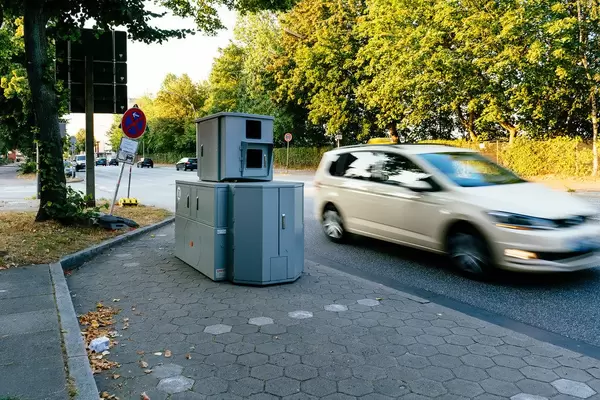 Speeding yellow taxi next to the portable speed radar unit on the street