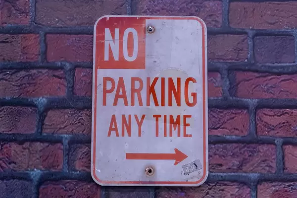 Spezielles Parkverbotsschild mit roter Aufschrift NO PARKING ANY TIME an Backsteinmauer