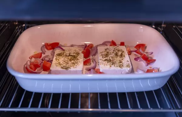 Spiced feta cheese with tomatoes and onions in the oven