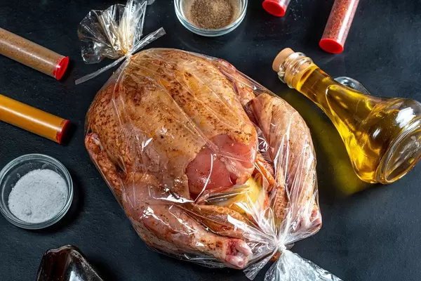 Spiced raw chicken stuffed with apples in a baking sleeve