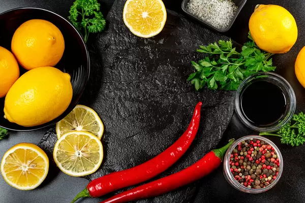 Spices and lemons on a dark background, top view