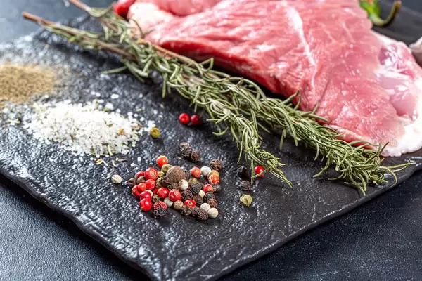 Spices and raw meat steak on black background