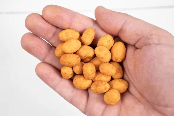 Spicy Peanuts in the hand above white wooden table (Flip 2020)