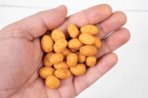 Spicy Peanuts in the hand above white wooden table