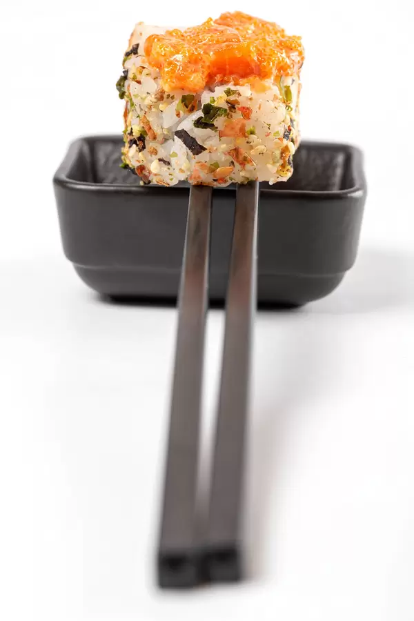 Spicy roll with tobiko caviar, sauce and chopsticks