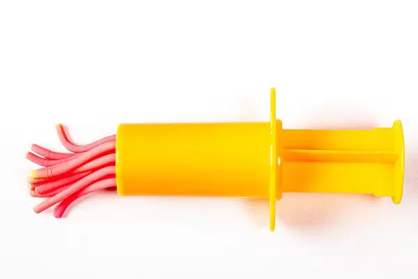 Spielzeug: gelbe Gebäckspritze und Teig auf weißem Hintergrund