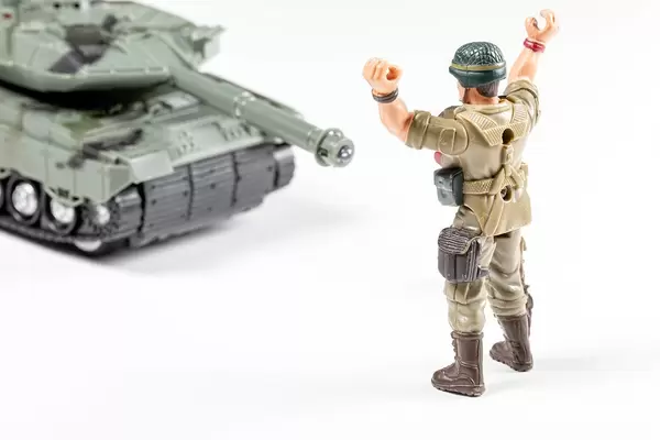 Spielzeug Soldat hält seine Hände hoch vor einem Panzer Konzept Kampf gegen den Verlierer