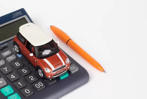 Spielzeugauto auf Taschenrechner mit Kugelschreiber