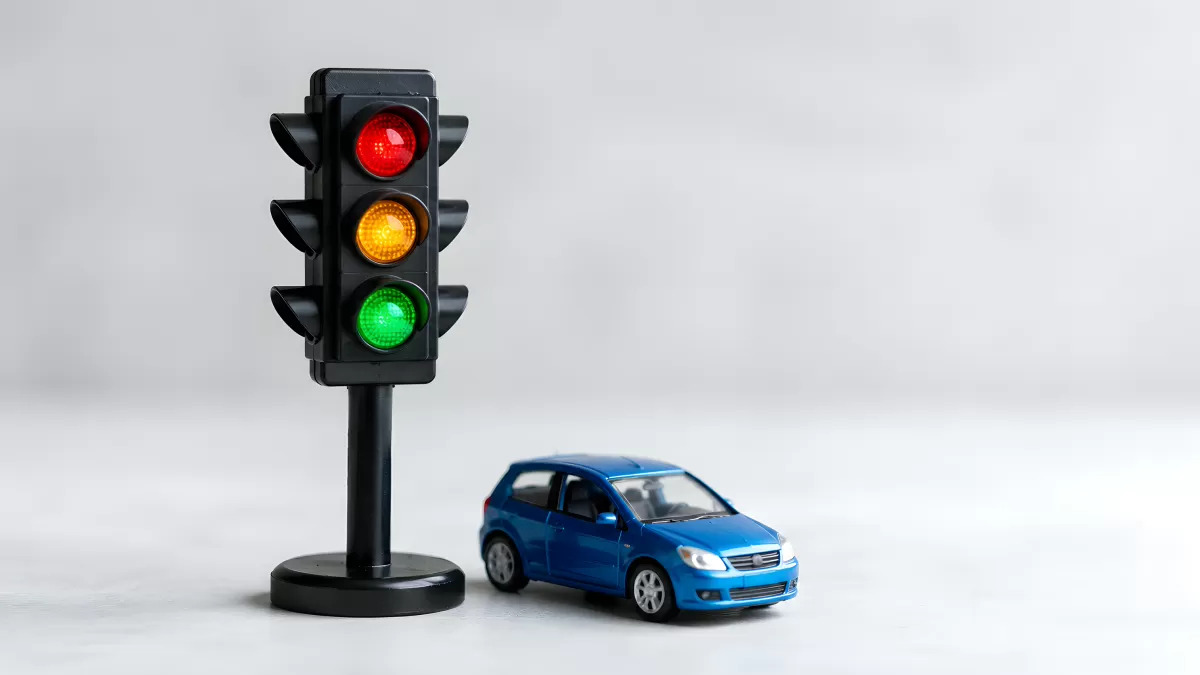 Spielzeugauto neben roter Ampel auf weißem Hintergrund