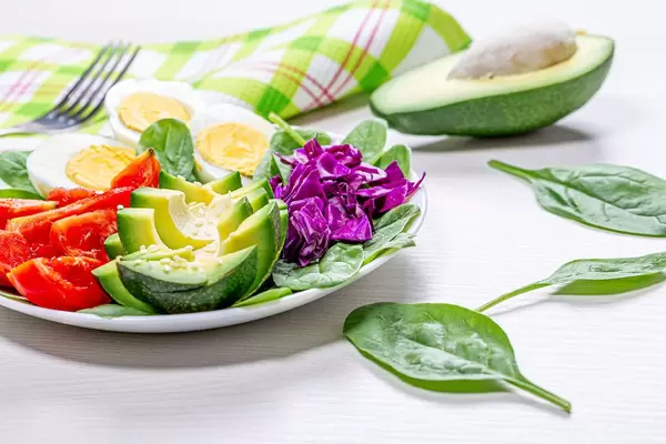 Spinach leaves with fresh chopped vegetables and boiled chicken eggs on a plate (Flip 2019)