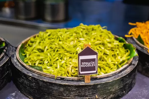 Spinach noodles on wooden bowl