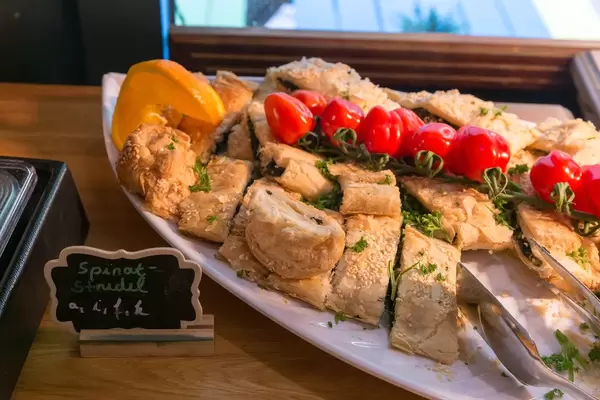 Spinatstrudel im Blätterteig mit Sesamkernen und mit Tomaten dekoriert