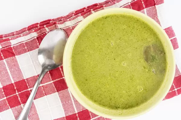 Spinatsuppe in einer Schüssel, neben einem Löffel