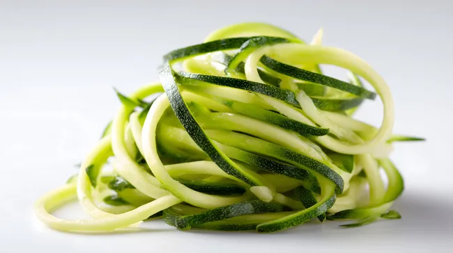 Spiralförmige Zucchininudeln auf weißem Hintergrund