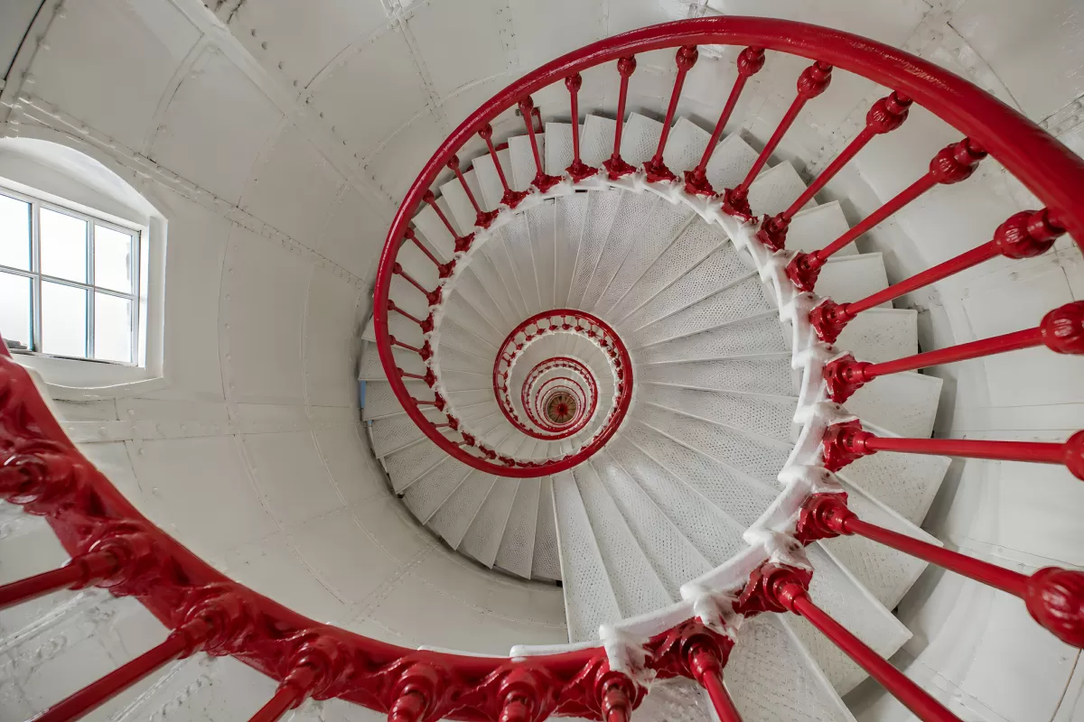 Spiraltreppe mit rotem Geländer von unten fotografiert