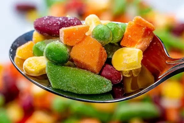 Spoon with peas, corn, beans with pieces of carrot and asparagus closeup (Flip 2019)