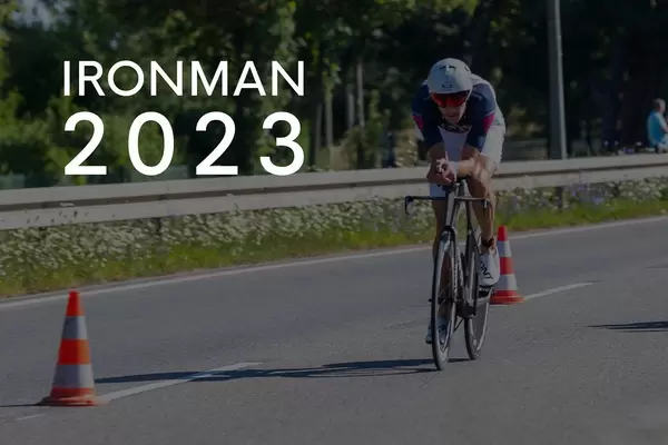 Sportler beim Radrennen während des Triathlons, neben dem Bildtitel "Ironman 2023"