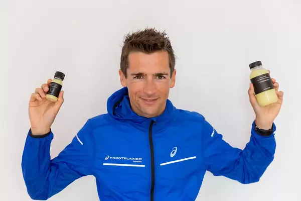 Sportler und Marathonläufer hält die veganen, glutenfreien "Ingwerling" Ingwershots von Kaltpresse in den Händen