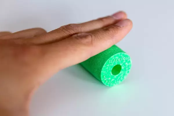 Sportlicher Mann trainiert mit der Blackroll Faszienrolle, zur Vorbeugung und Behandlung von Verspannungen und Stärkung der Handmuskulatur