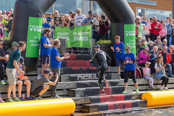 Sports athlete at the finish line for the swimming competition at the Ironman 70.3. at the coast of Lahti, Finland, with a cheering crowd