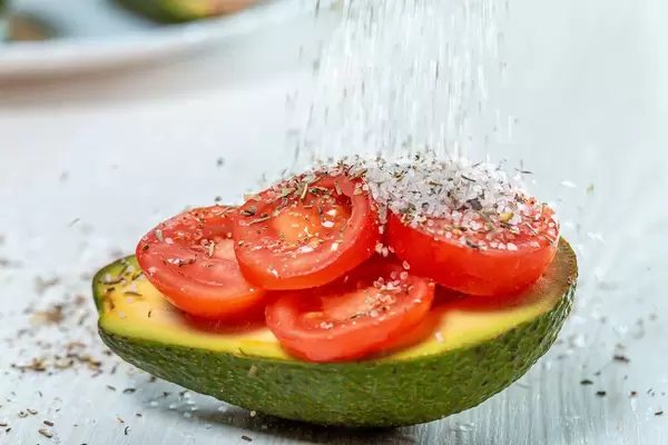 Sprinkle salt and spices on avocado stuffed with tomatoes (Flip 2019)