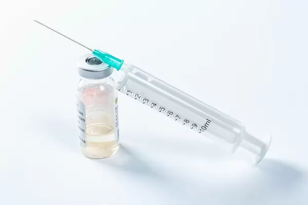 Spritze liegt auf Ampulle mit Antibiotika-Medikament vor weißem Hintergrund