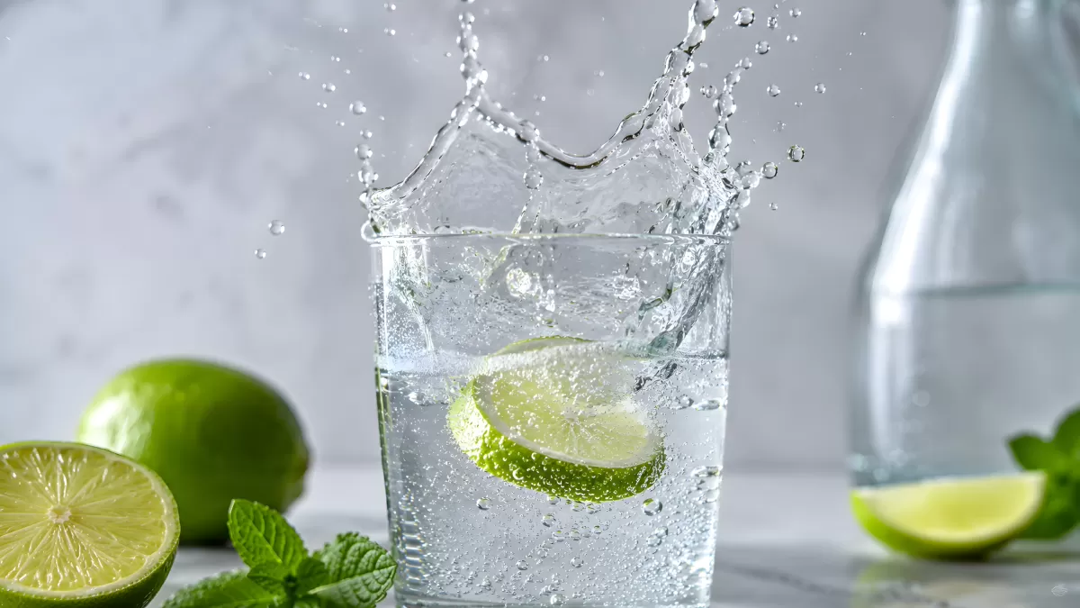 Spritzendes Wasser im Glas mit frischen Limettenscheiben