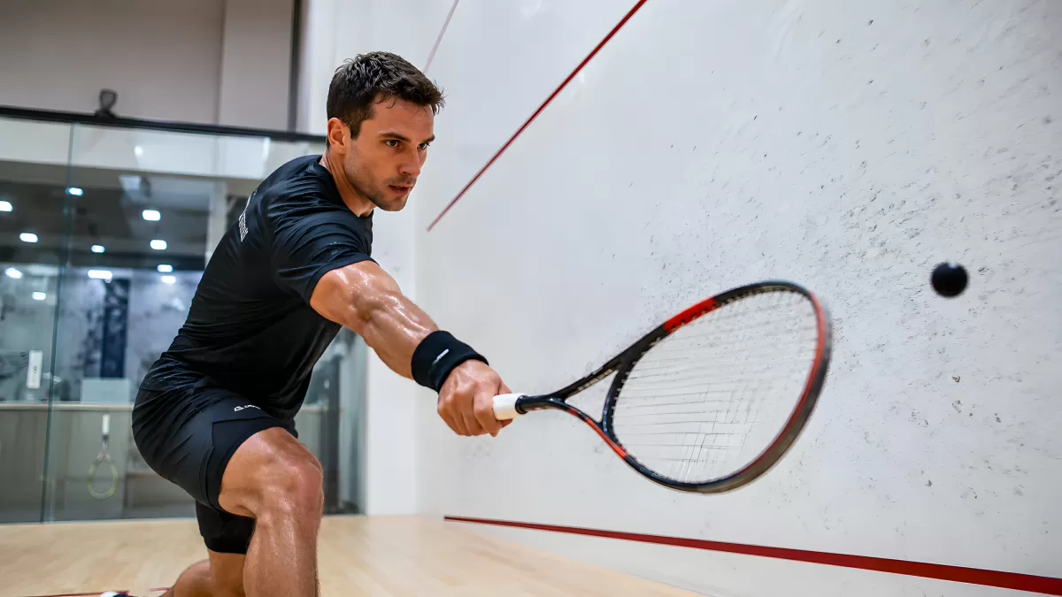 Squash-Spieler beim kraftvollen Rückhand-Schlag an der Wand