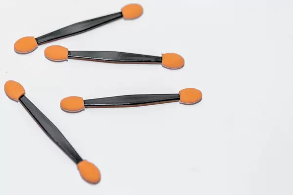 Stäbchen mit Makeup-Schwämmchen für Lidschatten auf beiden Seiten vor weißem Hintergrund