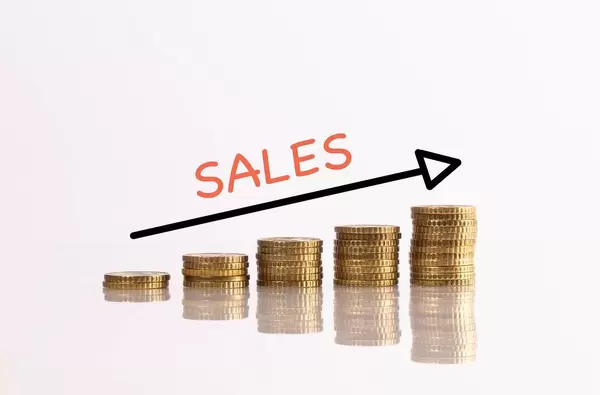 Stack of coins with arrow and sales text