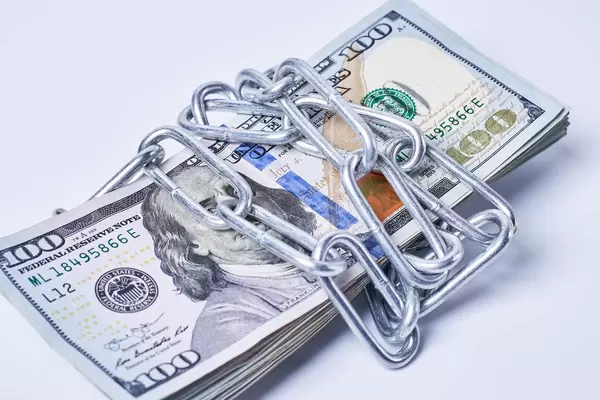 Stack of money wrapped by metal chain on white background