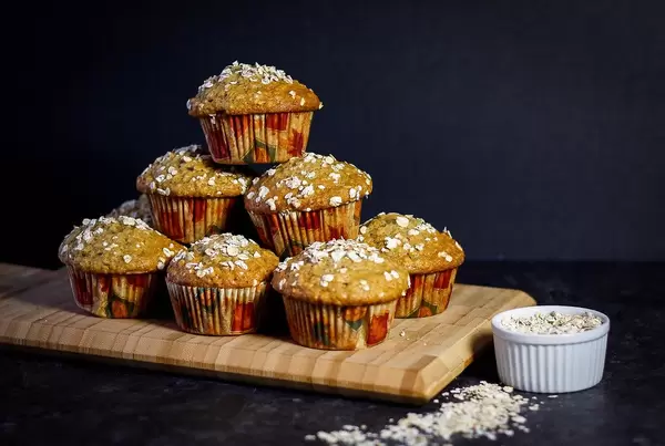 Stack of Oatmeal Muffins on a Wooden Cutting Board on Dark Background